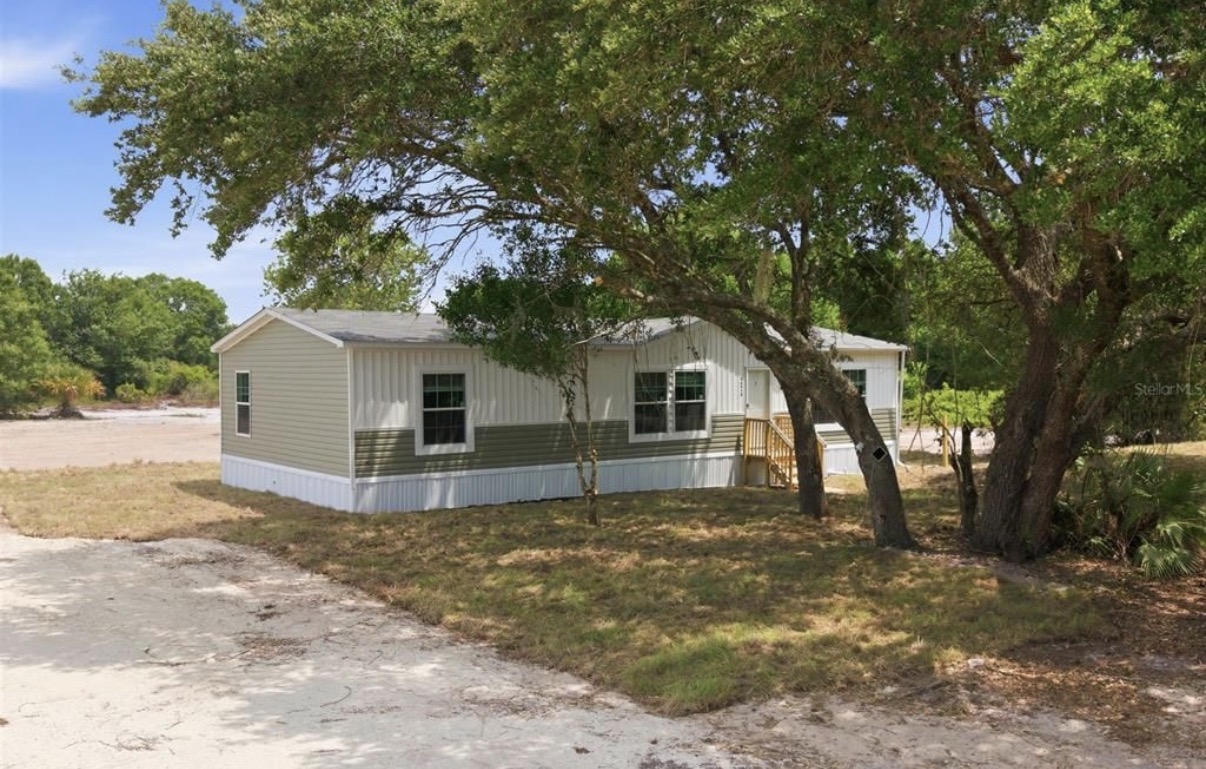 Manufactured home under large oak tree — Florida House Buyers